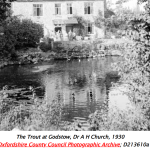 a pub on the bank of a river, water in the foreground.