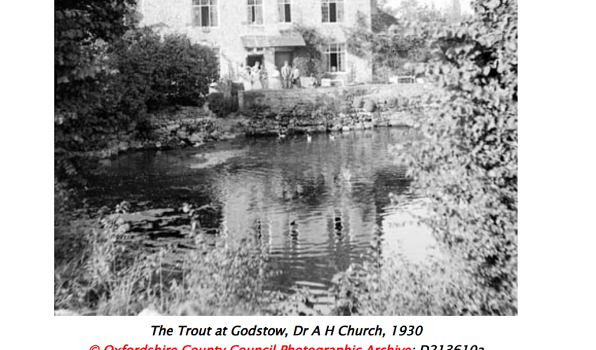 a pub on the bank of a river, water in the foreground.